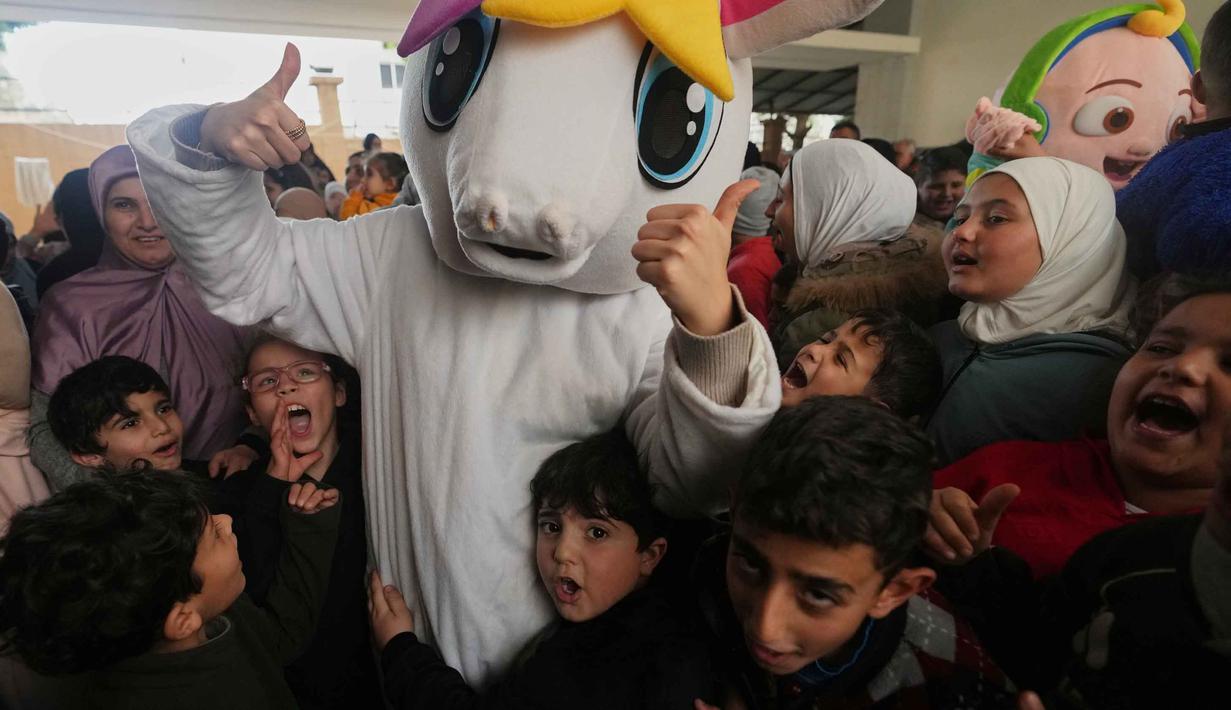Kehadiran sejumlah relawan yang mengenakan kostum tokoh menambah kegembiraan anak-anak saat merayakan Hari Raya Idulfitri. Tampak dalam foto, seseorang yang mengenakan kostum berpose dengan anak-anak pengungsi yang merayakan hari raya Idulfitri, di sebuah universitas negeri yang diubah menjadi tempat penampungan setelah serangan udara Israel di Beirut, Lebanon, Jumat, 20 Maret 2026. (AP Photo/Hassan Ammar)