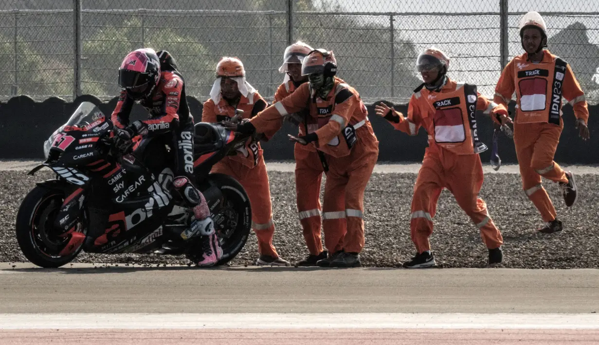 Sejumlah petugas lintasan tengah membantu pembalap Aprilia, Aleix Espargaro setelah terjatuh dari motornya  saat sesi latihan bebas MotoGP Indonesia 2023 di Sirkuit Mandalika, Lombok, Nusa Tenggara Barat, Jumat (13/10/2023). (AFP/Sonny Tumbaleka)