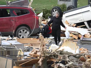Seorang wanita berjalan melewati puing-puing yang menumpuk di luar sebuah restoran yang hancur akibat tornado pada 15 Maret 2024 di Winchester, Indiana. (Scott Olson/Getty Images North America/Getty Images via AFP)