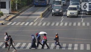 Warga beraktivitas menggunakan payung saat suhu udara mencapai 35 derajat Celcius di Kawasan Jalan MH Thamrin, Jakarta, Selasa (22/10/2019). (Liputan6.com/Helmi Fithriansyah) Event