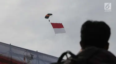 Prajurit Polairud melakukan aksi terjun payung sambil membentangkan bendera Merah Putih pada peringatan Hari Ulang Tahun (HUT) ke-67 Korps Polisi Air dan Udara di Lapangan Udara Pondok Cabe, Tangerang Selatan, Selasa (5/12). (Liputan6.com/Faizal Fanani)