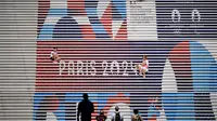 Orang-orang berpose di tangga dekat logo Olimpiade Paris 2024 di La Defense Paris, beberapa hari jelang upacara pembukaan. (AFP/Loic Venance)