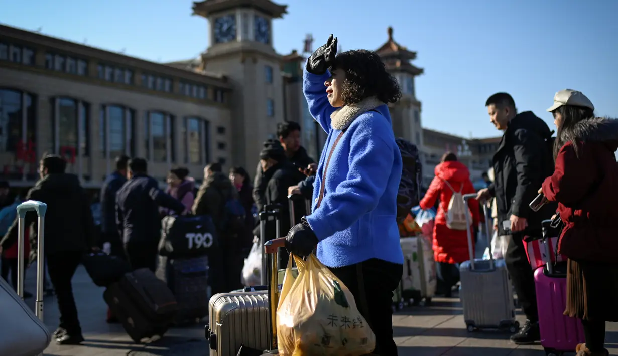Seorang wanita dengan koper dan bawaannya menunggu untuk masuk ke stasiun kereta api Beijing, Jumat (10/1/2020). Puluhan ribu warga China telah meninggalkan kota-kota besar China menuju kampung halaman, guna merayakan Tahun Baru Imlek yang akan jatuh pada 25 Januari mendatang. (WANG ZHAO/AFP)