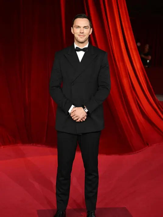 Nicholas Hoult mengenakan setelan hitam double breasted, kemeja tuksedo poplin putih dan dasi kupu-kupu satin hitam. Sepatu kulit hitam yang disikat. [Prada]