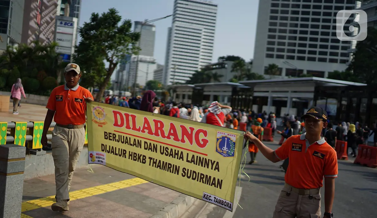 Spanduk larangan berjualan yang dibentangkan petugas Satpol PP di jalur Hari Bebas Kendaraan Bermotor atau Car Free Day, Jakarta, Minggu (3/11/2019). Pemprov DKI melarang PKL berjualan di sepanjang jalur Car Free Day yang selama ini memenuhi jalan serta trotoar. (Liputan6.com/Immanuel Antonius)