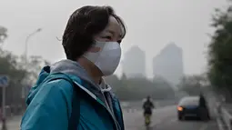 Seorang wanita beraktivitas mengenakan masker pelindung untuk menghindari polusi udara buruk di Beijing (22/10). (AFP Photo/Nicolas Asfaouri)