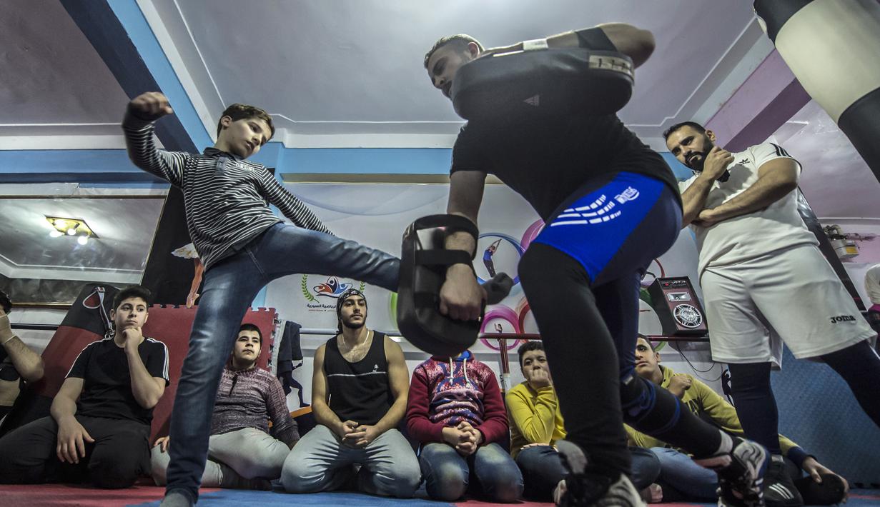 Pengungsi Suriah Amir al-Awad (kaos putih) melihat siswanya berlatih tendangan di Akademi Olahraga Suriah di Alexandria, Mesir (4/1). Akademi ini menjadi tempat latihan khususnya anak-anak untuk belajar bela diri. (AFP/Khaled Desouki)