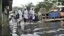 Sejumlah anak sekolah melintasi banjir yang masih merendam Kampung Rawa Indah, Jakarta Utara, Senin (24/2/2020). Kampung yang terletak di dua kelurahan, yakni Sukapura dan Pegangsaan Dua tersebut masih terendam banjir hingga sore ini dengan ketinggian air 30-50 cm. (merdeka.com/Iqbal S Nugroho)