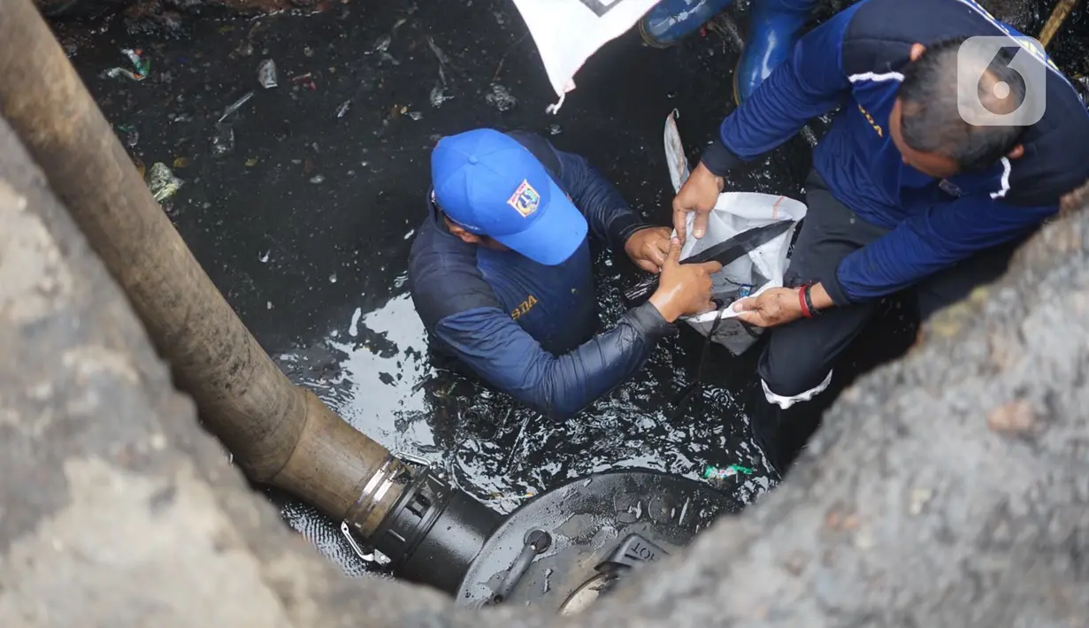 Petugas Sudin Sumber Daya Air Jakarta Timur membersihkan saluran gorong-gorong yang tertutup lumpur dan sampah di kawasan Pasar Rebo, Kamis (19/3/2020). Pembersihan untuk memperlancar sistem drainase yang tersumbat dan kerap menimbulkan genangan air di kawasan itu. (Liputan6.com/Immanuel Antonius)