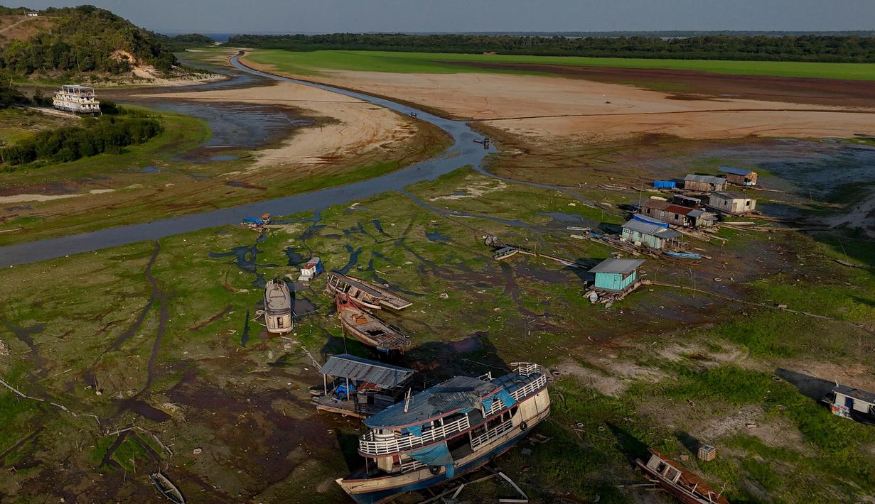 Perahu dan rumah-rumah terlihat terdampar di Danau Aleixo akibat kekeringan parah di sebelah barat Manaus, Negara Bagian Amazonas, Brasil, pada 20 September 2024. (MICHAEL DANTAS/AFP)