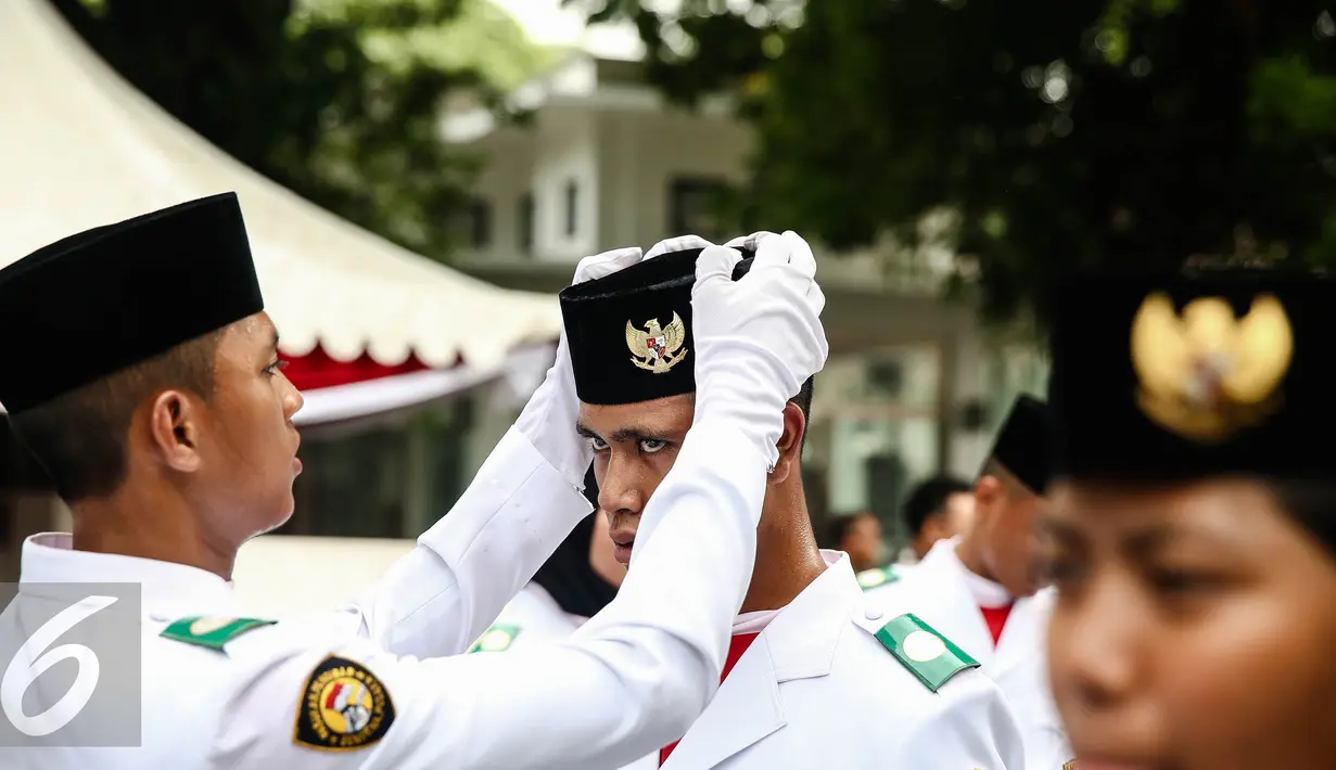 Anggota pria paskibraka 2016 merapikan peci rekannya saat bersiap melaksanakan gladi bersih upacara HUT ke-71 Kemerdekaan RI di Istana Merdeka, Jakarta, Senin (15/8). (Liputan6.com/Faizal Fanani)