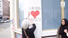Seorang wanita Inggris dan wanita muslim tampak sedang bersatu memasang sebuah poster dengan tulisan London Heart United.
