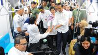 Presiden Joko Widodo didampingi Ibu Negara Iriana Widodo bersalaman dengan penyandang disabilitas saat menjajal MRT di Jakarta, Kamis (21/3). (Liputan6.com/Angga Yuniar)