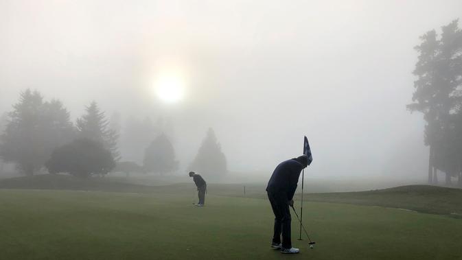 Para pegolf bermain dalam kabut tebal di Lapangan Golf Russley di Christchurch, Selandia Baru, Sabtu (25/5/2019). Beberapa penerbangan di Bandara Christchurch ditunda atau dibatalkan karena kabut tebal menyelimuti kota tersebut. (AP Photo/Mark Baker)