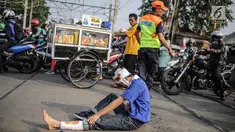 Aksi teatrikal saat petugas PT KAI Daop I menggelar sosialisasi tertib berlalu lintas di pintu perlintasan sebidang kawasan Bukit Duri, Jakarta, Selasa (17/9/2019). Sosialisasi dilakukan karena banyaknya kecelakaan akibat ketidakdisiplinan pengendara. (Liputan6.com/Faizal Fanani)
