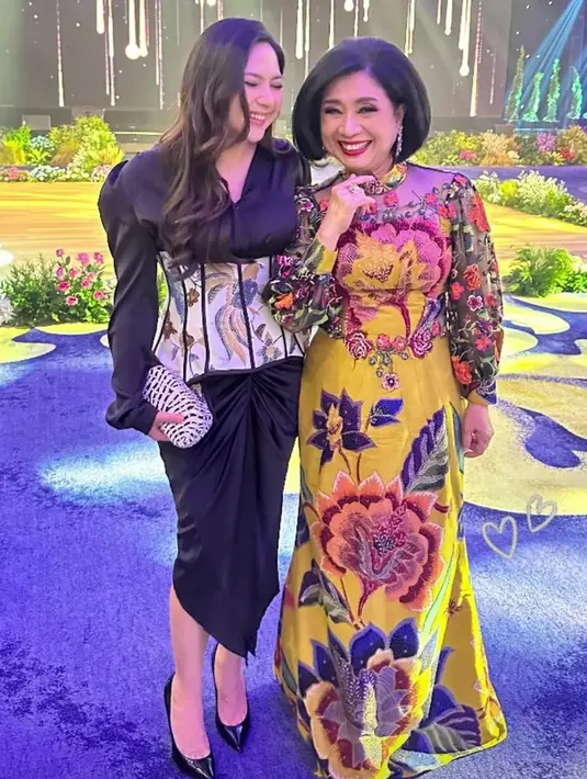 Melengkapi tampilannya dengan stiletto heels hitam, sambil membawa clutch putih hitam. Membuat tampilan Jessica semakin elegan. Sang ibu mertua yang berfoto di sebelahnya tampil lebih bright dengan dress kuning bermotif. [@jscmila]