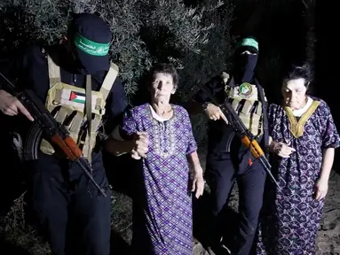 Yocheved Lifshitz (85, tengah) dan Nurit Cooper (79) dikawal oleh Hamas saat mereka dilepaskan ke Palang Merah di lokasi yang tidak diketahui, Senin (23/10/2023). (Al Qassam brigades via AP)
