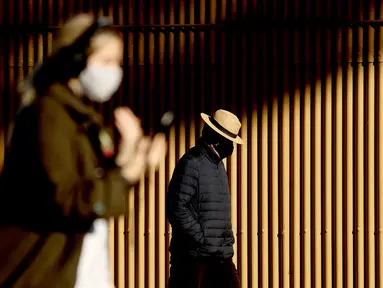 Orang-orang berjalan di sepanjang Circular Quay, Sydney, Australia, Selasa (13/7/2021). Lima juta penduduk Sydney akan berada dalam lockdown COVID-19 untuk dua minggu lagi. (Brendon THORNE/AFP)