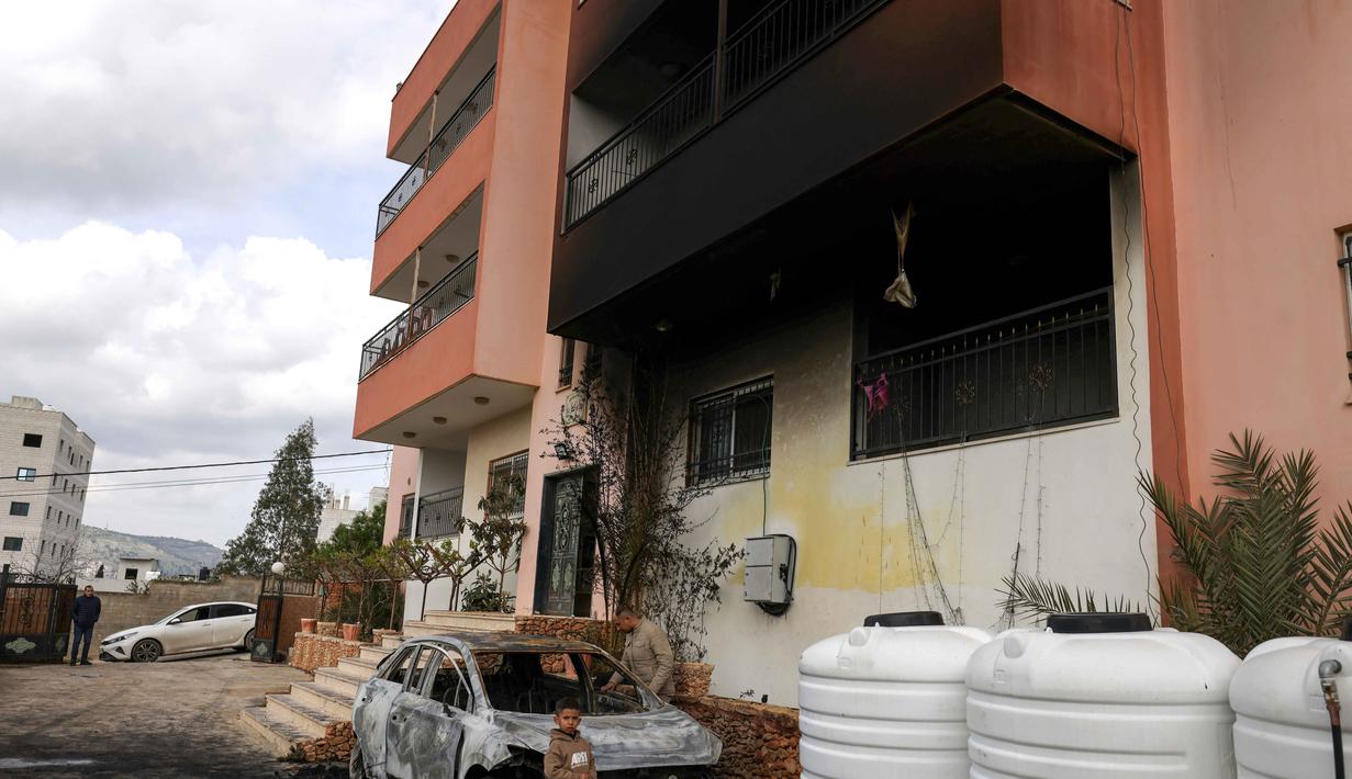 Warga Palestina mengatakan pada Minggu 22 Maret 2026 pemukim Israel membakar bangunan dan mobil dalam serangan terhadap sejumlah desa di Tepi Barat yang diduduki. Tampak dalam foto, seorang anak Palestina berdiri di luar mobil yang hancur dan rumah yang terbakar setelah serangan yang dilaporkan dilakukan oleh pemukim Israel di desa Deir al-Hatab, sebelah timur kota Nablus, di Tepi Barat, wilayah yang diduduki Israel pada Senin 23 Maret 2026. (JAAFAR ASHTIYEH/AFP)