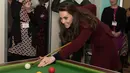 Kate Middleton bersiap memukul bola ketika bermain biliar saat kunjungannya ke MIST, sebuah tempat kesehatan mental bagi anak di Pontypool, Wales, Inggris (22/2). Kate terlihat menikmati permainan biliar tersebut. (AFP Photo / Pool / Paul Edwards)