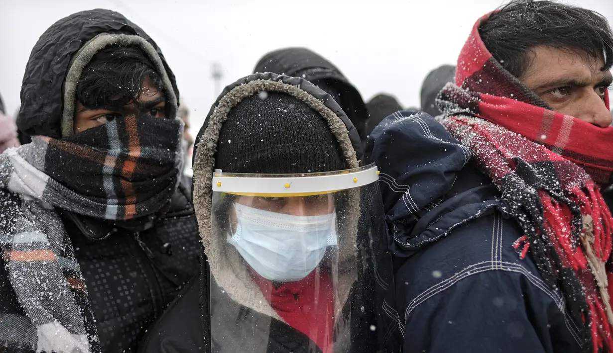 Migran menunggu untuk dipindahkan selama hujan salju di kamp Lipa, barat daya Bosnia, dekat perbatasan dengan Kroasia, Sabtu (26/12/2020). Ratusan migran terdampar di tenda-tenda kumuh dan terbakar di Bosnia, di tengah hujan salju yang lebat dan suhu membeku. (AP Photo/Kemal Softic)
