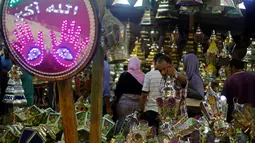 Calon pembeli saat melihat - lihat kios yang berjualan lentera khas Ramadan dan beraneka lampu di pasar Sayida Zienab, Mesir 6 Juni 2016. Lentera yang dijual beraneka ragam dengan kaligrafi Arab yang menawan. (REUTERS / Amr Abdallah Dalsh)