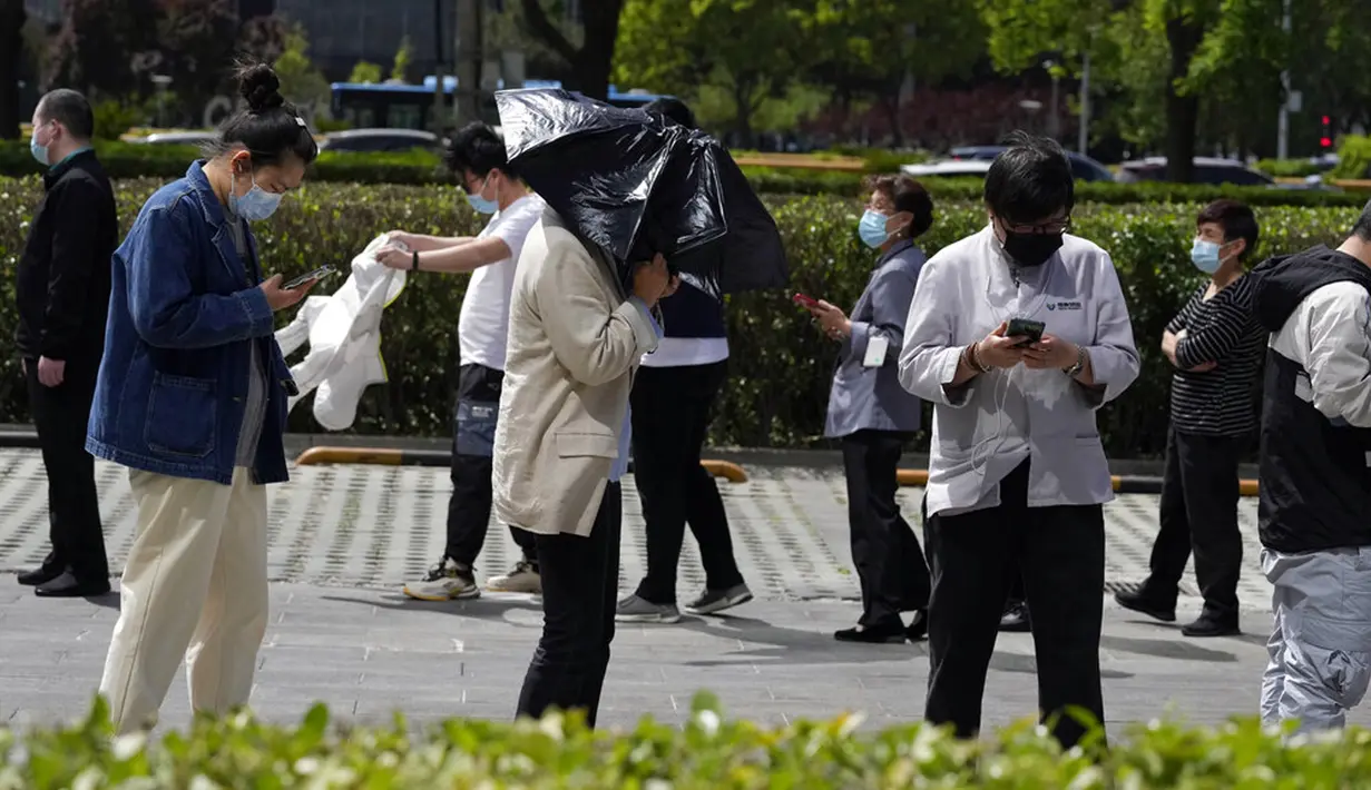 <p>Warga mengantre untuk tes COVID-19 di luar gedung perkantoran di Distrik Haidian, Beijing, China, Selasa (26/4/2022). Beijing memberlakukan pengujian massal dan menutup akses ke lingkungan karena berupaya menahan wabah COVID-19 baru. (AP Photo/Ng Han Guan)</p>