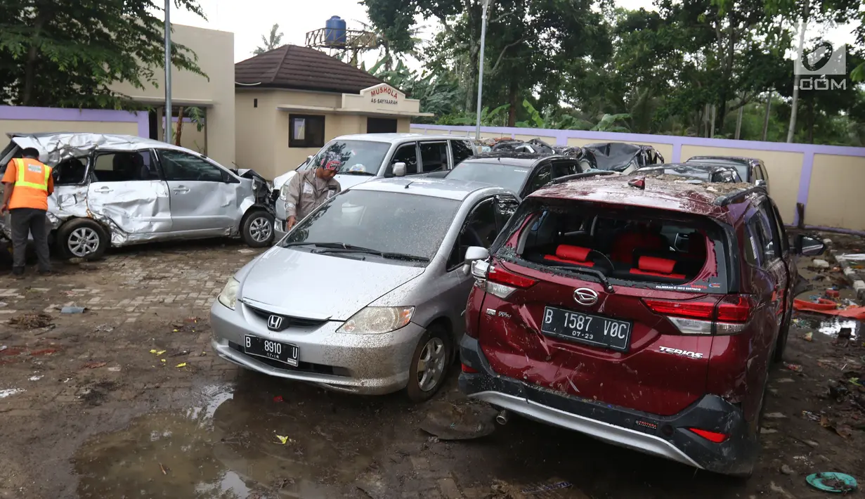 Petugas makukan evakuasi mobil yang rusak akibat terjangan Tsunami Selat Sunda di Terminal Carita, Banten, Selasa (25/12). Di terminal ini pemilik mobil dapat mengambilnya yang disertai dengan STNK. (Liputan6.com/Angga Yuniar)