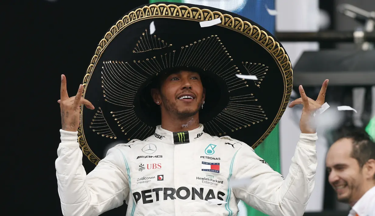 Pembalap Mercedes dari Inggris, Lewis Hamilton mengenakan topi sombrero merayakan keberhasilannya menjuarai balapan GP Meksiko di Autodromo Hermanos Rodriguez, Mexico City (28/10/2019). Kemenangan ini mendekatkan Hamilton ke titel juara dunia F1 2019. (AP Photo/Rebecca Blackwell)