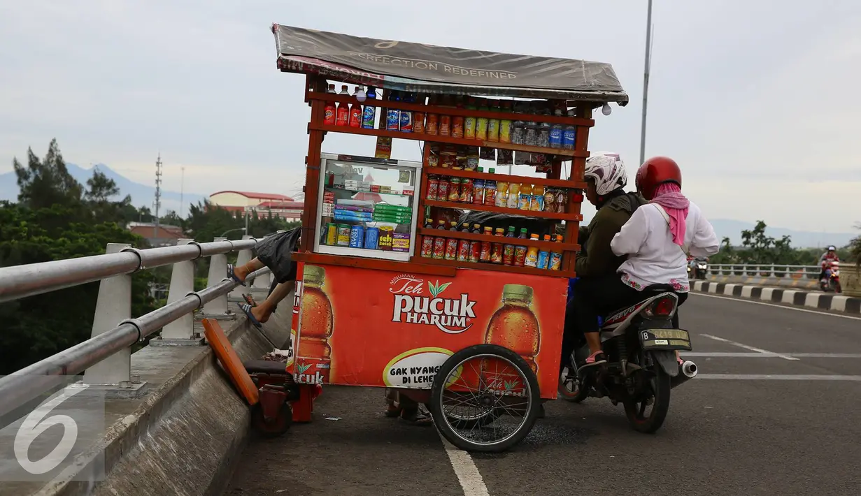 Pedagang minuman menjajakan dagangan menggunakan gerobak di atas jalan layang Pasar Rebo, Jakarta, Sabtu (14/1). Padahal aktivitas tersebut berbahaya bagi keselamatan mereka serta pengendara lain. (Liputan6.com/Immanuel Antonius)