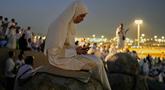 Seorang jemaah Muslim menggunakan telepon seluler untuk membaca ayat-ayat dari Al-Quran di atas bukit berbatu yang dikenal sebagai Jabal Rahmah atau Gunung Rahmat, di Dataran Arafah, selama ibadah haji tahunan di dekat kota suci Mekah, Arab Saudi, Selasa 26 Mei 2026. (AP Photo/Altaf Qadri)