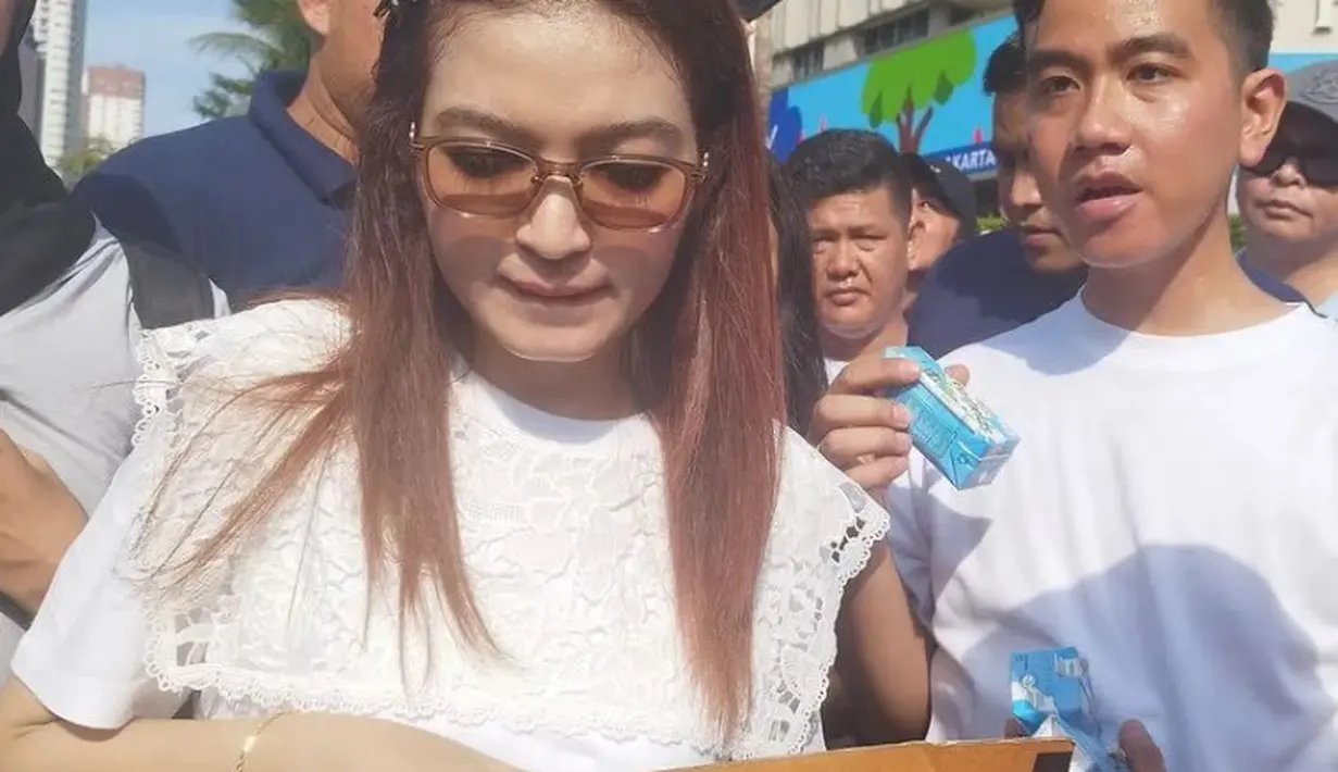 Sambil memberikan susu, tampak Selvi mengenakan atasan putih lengan pendek dengan aksen lace di bagian dada. Ia pun mengenakan sunglassnya. [@selvie_anada_]