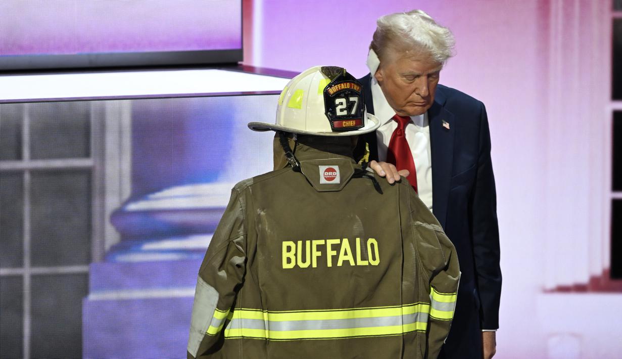 Donald Trump berdiri di samping jaket dan helm Corey Comperatore. (AP Photo/Charles Rex Arbogast)