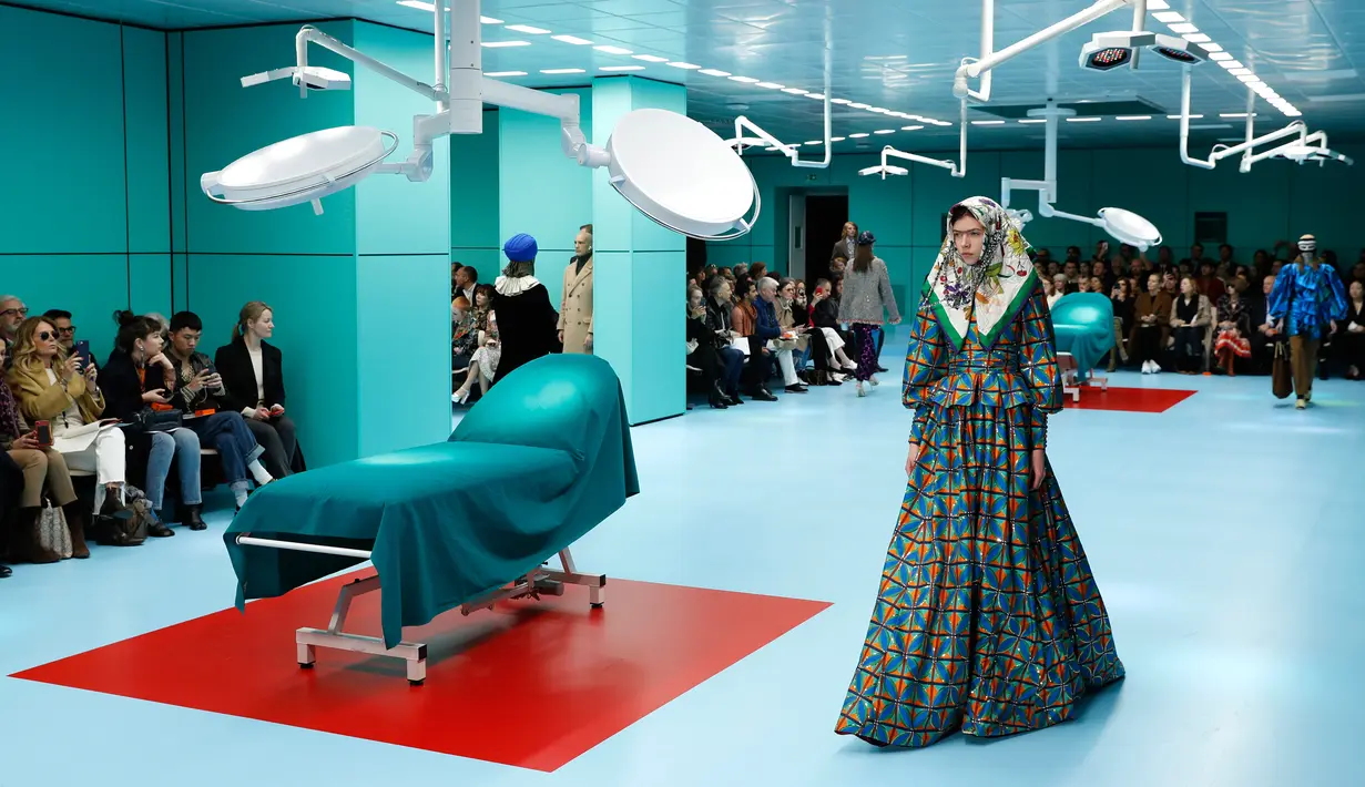Seorang model dengan scarf menyerupai hijab di kepalanya menampilkan koleksi terbaru Gucci FW18 dalam Milan Fashion Week 2018, Rabu (21/2). Satu scarf bermotif bunga dengan tambahan aksesoris perak menjuntai di leher. (AP Photo/Antonio Calanni)