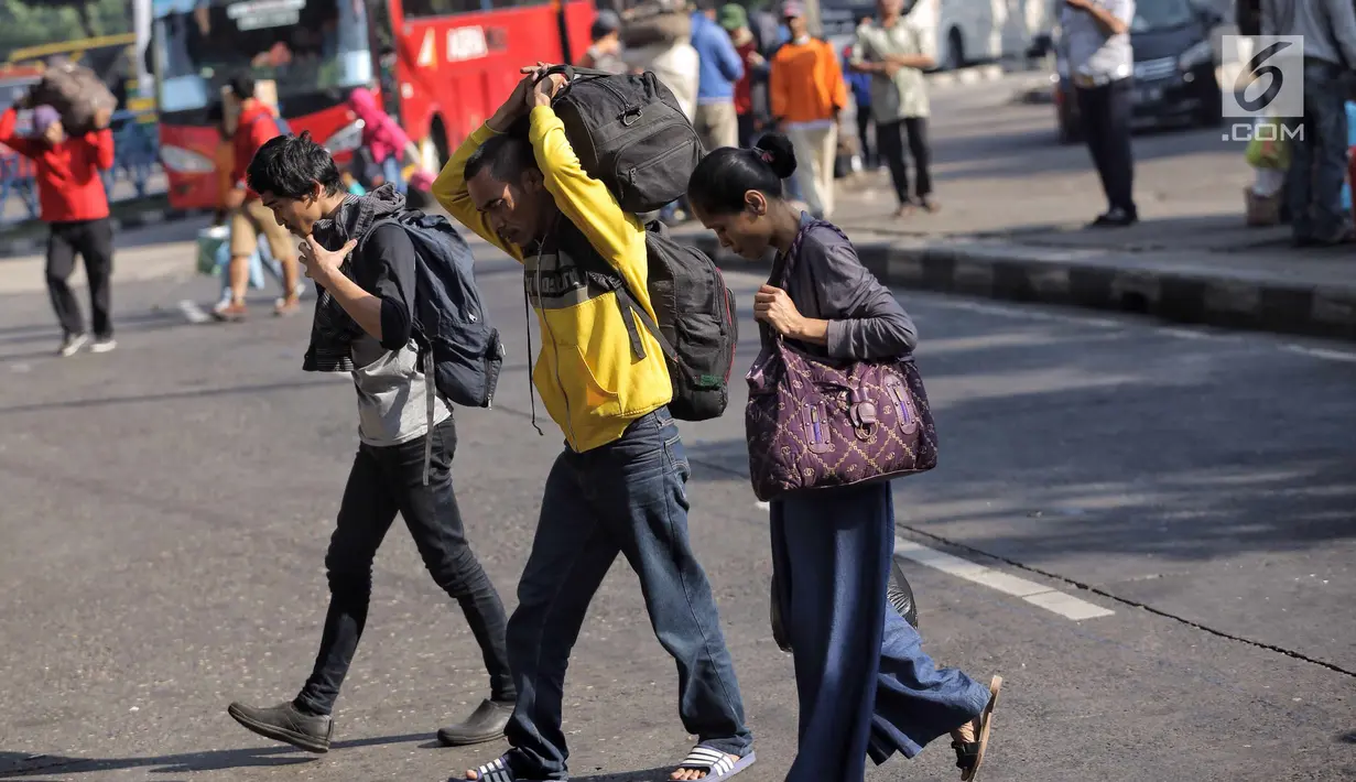 Penumpang membawa barang usai turun dari bus Antar Kota Antar Provinsi (AKAP) di Terminal Kampung Rambutan, Jakarta, Selasa (19/6). Terdapat 691 bus kedatangan hingga siang ini. (Liputan6.com/Faizal Fanani)