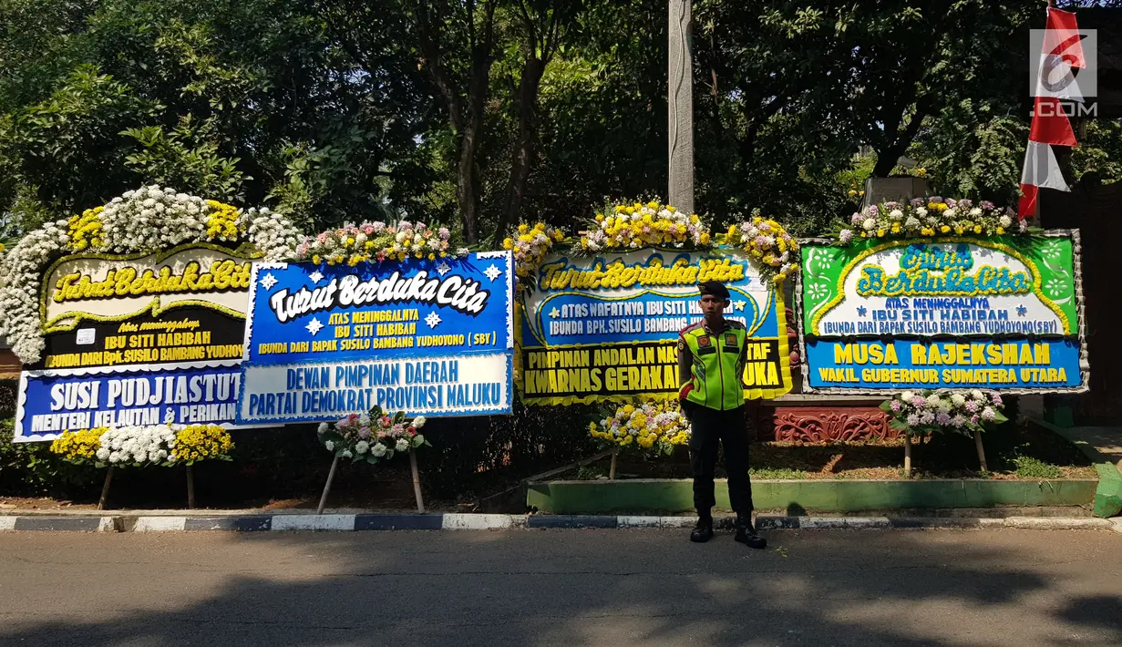 Polisi bediri dekat karangan bunga untuk almarhumah Siti Habibah, Ibunda Presiden ke-6 RI, Susilo Bambang Yudhoyono (SBY) di Puri Cikeas, Bogor, Sabtu (31/8/2019). Karangan bunga duka cita berdatangan di Puri Cikeas menyusul meninggalnya ibunda SBY pada Jumat (30/8). (Liputan6.com/Herman Zakharia)