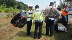 Petugas kepolisian mendata penumpang mobil Innova yang terbalik di KM 208 Tol Palikanci (Palimanan-Kanci), Jawa Barat, Rabu (21/6). Tak ada korban jiwa dalam kecelakaan yang diduga karena sopir mobil B 2247 TKL itu mengantuk. (Liputan6.com/Gempur M Surya)