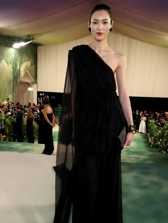 Model asal China, Liu Wen terlihat mengenakan dress Saint Laurent satu bahu berwarna hitam yang elegan, dipadukan dengan anting-anting piramida persegi dan slingback dari label tersebut. [@liuwenlw]