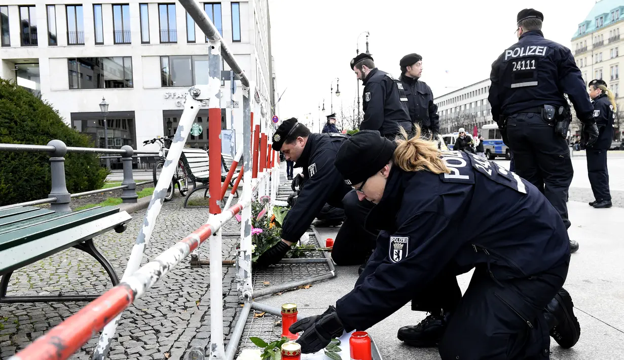 Polisi Jerman mengatur bunga yang dibawa oleh orang-orang di depan Kedutaan Besar Prancis di Berlin, Sabtu (14/11/2015). Karangan bunga tersebut untuk menghormati para korban serangan mematikan di Paris. (AFP Photo/ Tobias Schwarz)