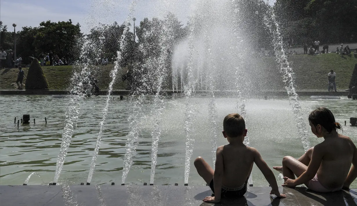 Anak-anak bermain air mancur di kolam di Trocadero Fountains dekat Menara Eiffel, Paris (22/7/2019). Warga Paris bersiap menghadapi suhu terpanas pada minggu ini ketika gelombang panas akan melanda ke Eropa utara. (AFP Photo/Alain Jocard)