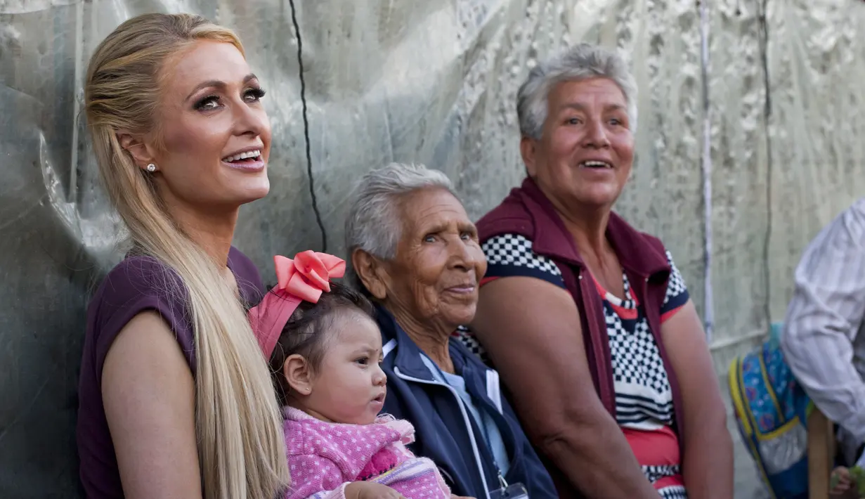 Paris Hilton berbincang dengan salah satu keluarga terkena dampak gempa bumi pada September 2017 di San Gregorio Atlapulco, Meksiko (12/11). Paris Hilton tampil mengenakan kaos, jeans dan sepatu hitam. (AFP Photo/Antonio Nava)