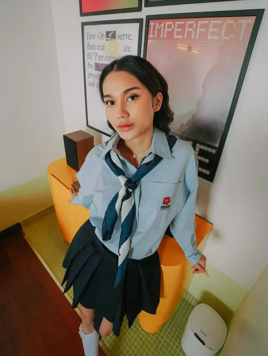 Azizah tampil manis dengan pleated skirt biru selutut. Penampilan Azizah semakin manis dengan syal biru-putih yang dililitkan di lehernya bagaikan dasi. [foto: Instagram/azizahsalsha_]