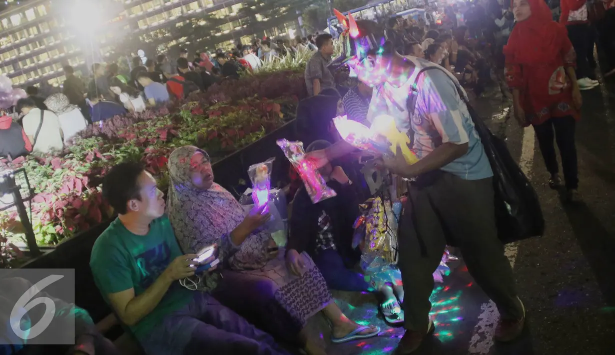Pedagang menjajakan dagangan saebelum perayaan malam tahun baru di kawasan Bundaran HI di Jakarta, Sabtu (31/12). Walaupun car free night dibatalkan kawasan tersebut mulai dipadati warga dari berbagai daerah. (Liputan6.com/Immanuel Antonius)