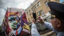 Petugas keamanan memotret mural bergambar bintang Portugal, Cristiano Ronaldo, yang dibuat untuk menyambut Piala Konfederasi di Kazan, Kamis (15/6/2017). (EPA/Mario Cruz)