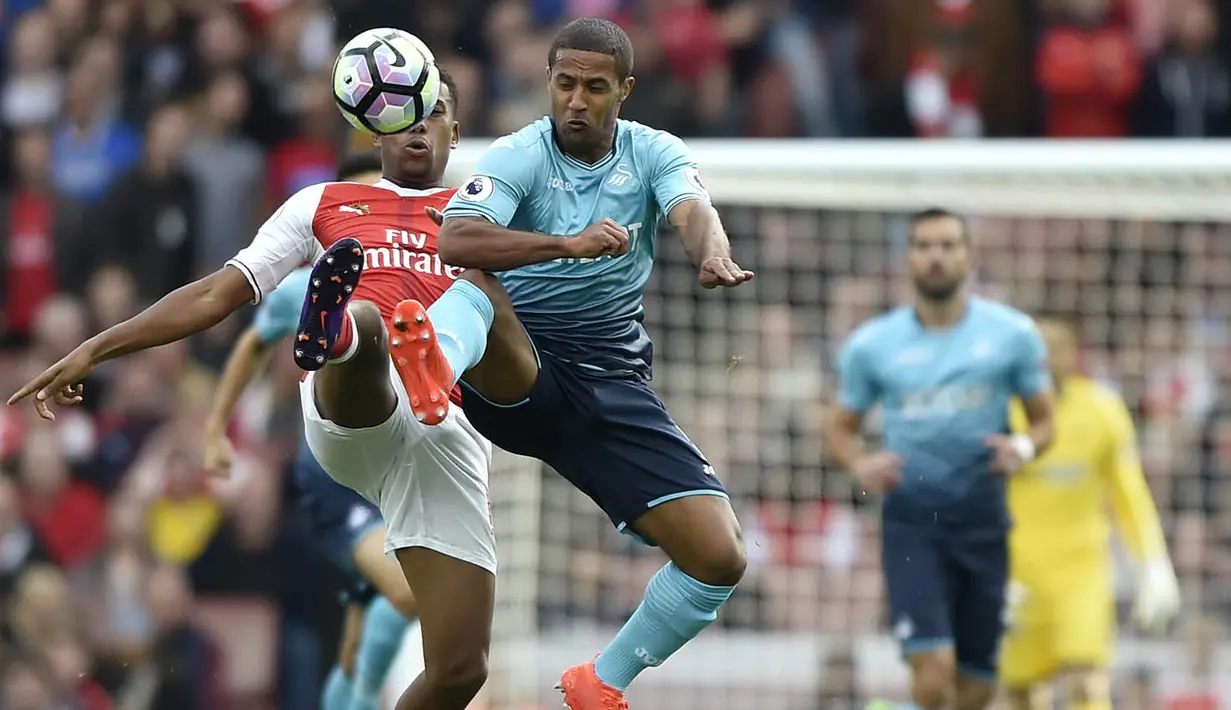 Penyerang Arsenal, Alex Iwobi, berebut bola dengan penyerang Swansea, Wayne Routledge, pada laga Premier League di Stadion Emirates, London, Sabtu (15/10/2016). Arsenal menang 3-2 atas Swansea. (Reuters/Hannah McKay)