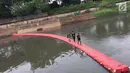 Anak-anak melintasi penyaring sampah untuk menyeberangi Kanal Banjir Timur di Jakarta, Kamis (28/12). Keberadaan penyaring sampah tersebut dimanfaatkan warga sebagai sarana menyeberang untuk mempersingkat waktu tempuh. (Liputan6.com/Immanuel Antonius)