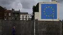 Warga melintasi mural karya seniman jalanan Banksy di dinding dekat terminal feri Dover, Kent, Inggris, Senin (8/5). Mural itu melukiskan seorang pria yang menaiki tangga dan menggugurkan salah satu bintang di bendera Uni Eropa. (DANIEL LEAL-OLIVAS/AFP)