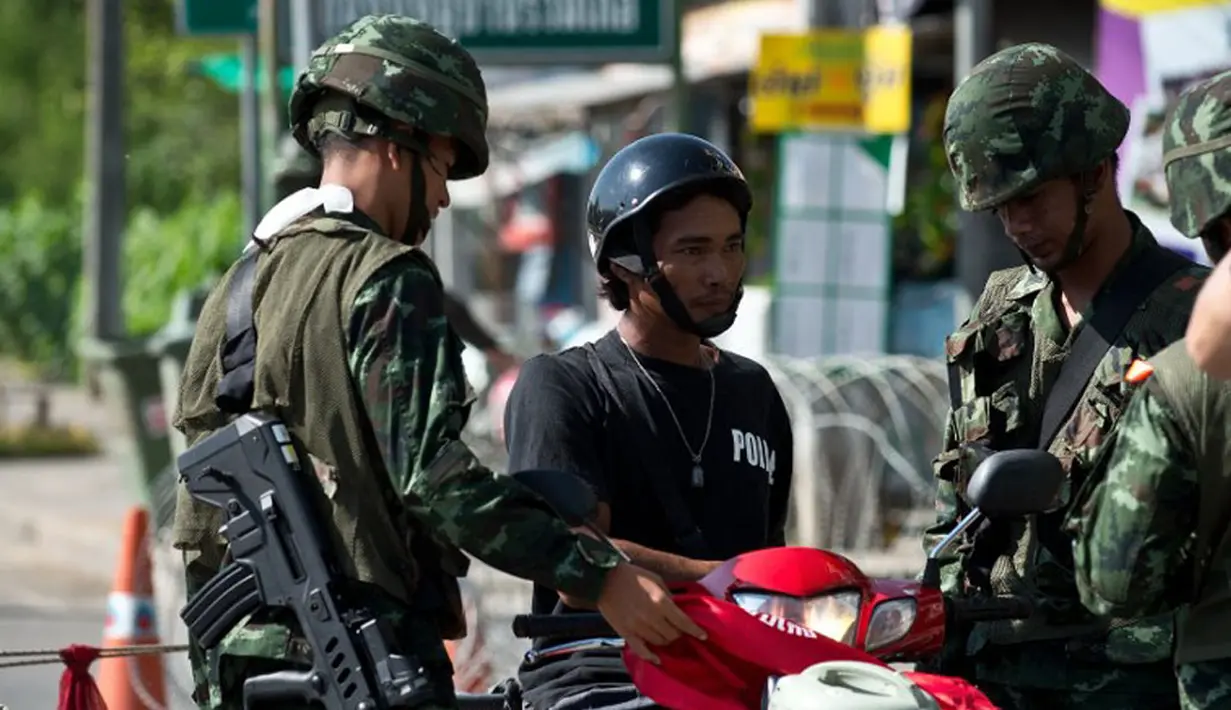 Tentara Thailand memeriksa pengendara motor di sebuah pos pemeriksaan yang ada di pinggiran kota Bangkok, Thailand, (22/5/2014). (AFP PHOTO/Manan Vatsyayana)