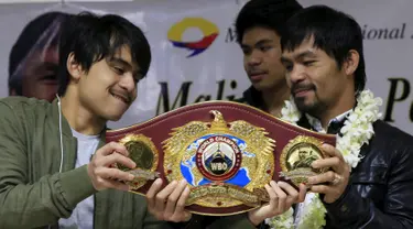 Petinju asal Filipina, Manny Pacquiao bersama putra sulungnya, Jimwell menunjukkan sabuk WBO kepada awak media usai mengalahkan Timothy Bradley setibanya di Bandara Internasional Ninoy Aquino, Manila (14/4). (REUTERS/Romeo Ranoco)