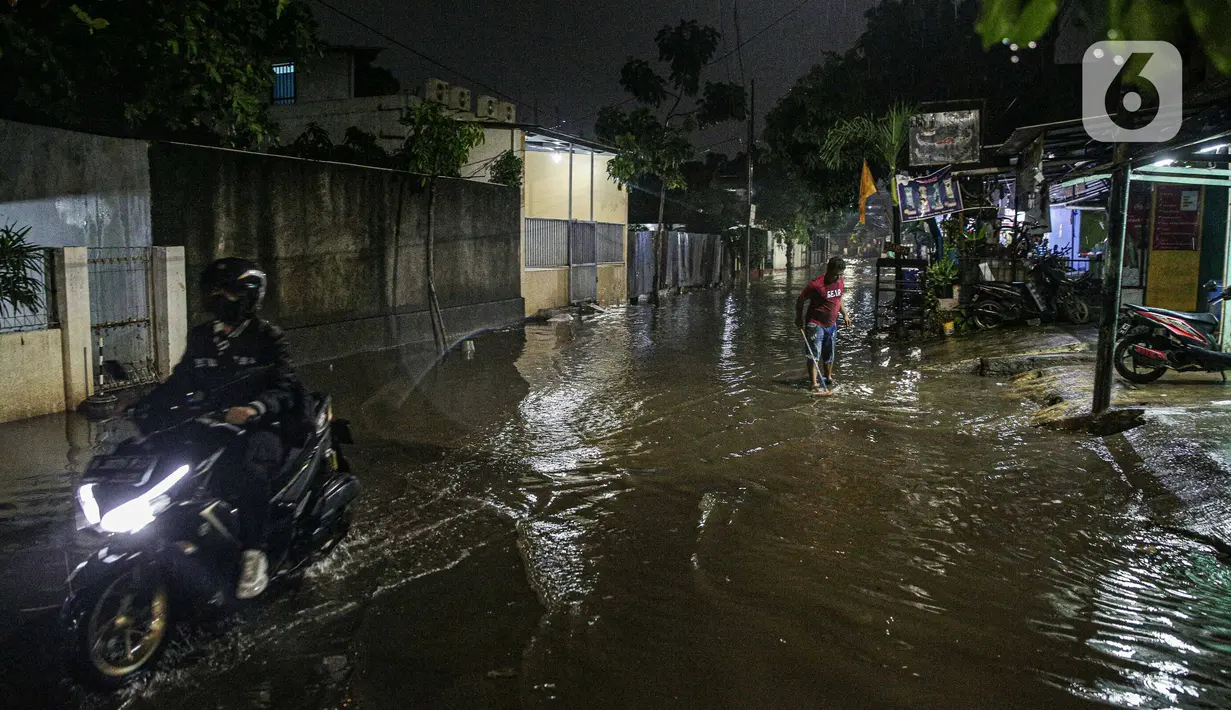 Warga melintas di genangan banjir di kawasan Mampang Prapatan, Jakarta, Sabtu (13/11/2021). Intensitas hujan yang tinggi sejak sore di Jakarta membuat kawasan permukiman di Mampang Prapatan tergenang banjir dengan tinggi sebetis orang dewasa. (Liputan6.com/Faizal Fanani)